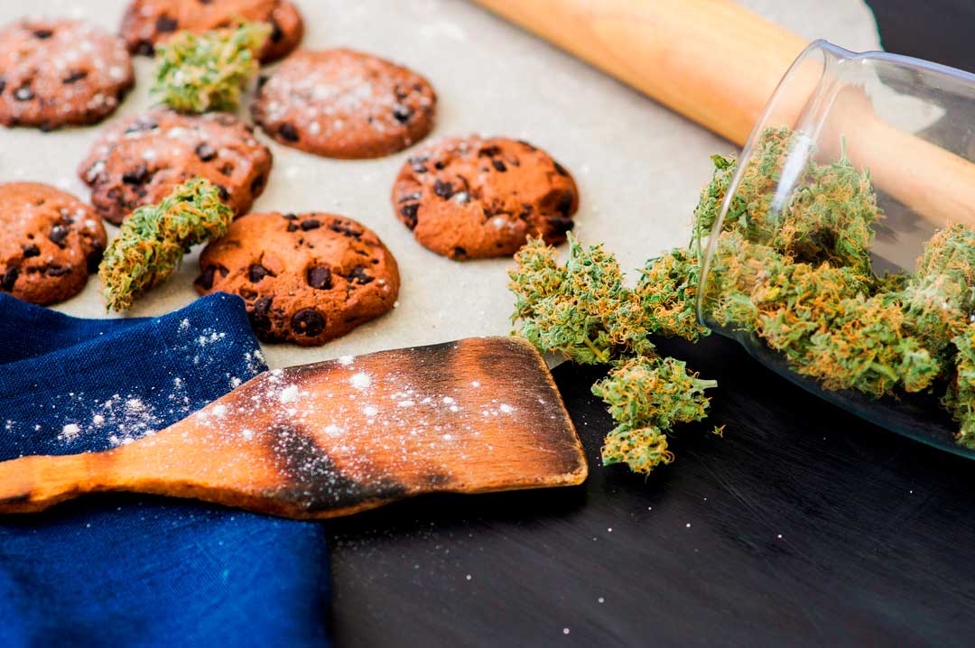 cannabis flower and cookies and flour kitchen tools on table