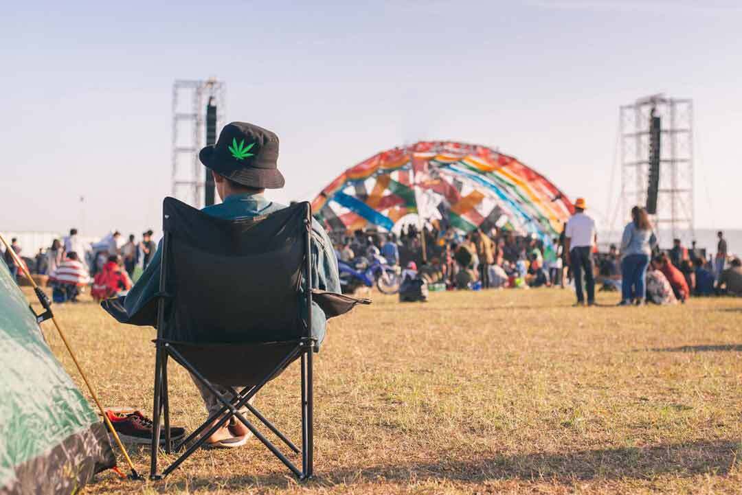 facebook group for cannabis photographers - image of dude sitting on a chair at an event wearing cannabis leaf hat