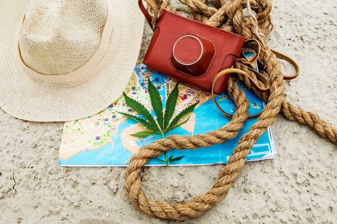 the sandbox cannabis photography innovations - cannabis leaf, map, camera, rope, and hat on beach