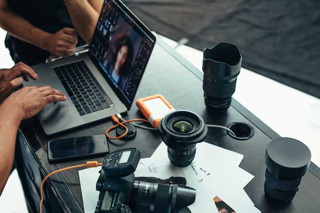 cannabis photography jobs and recruiting - image of photography equipment on desk with artists working on laptop with another remote collaborator